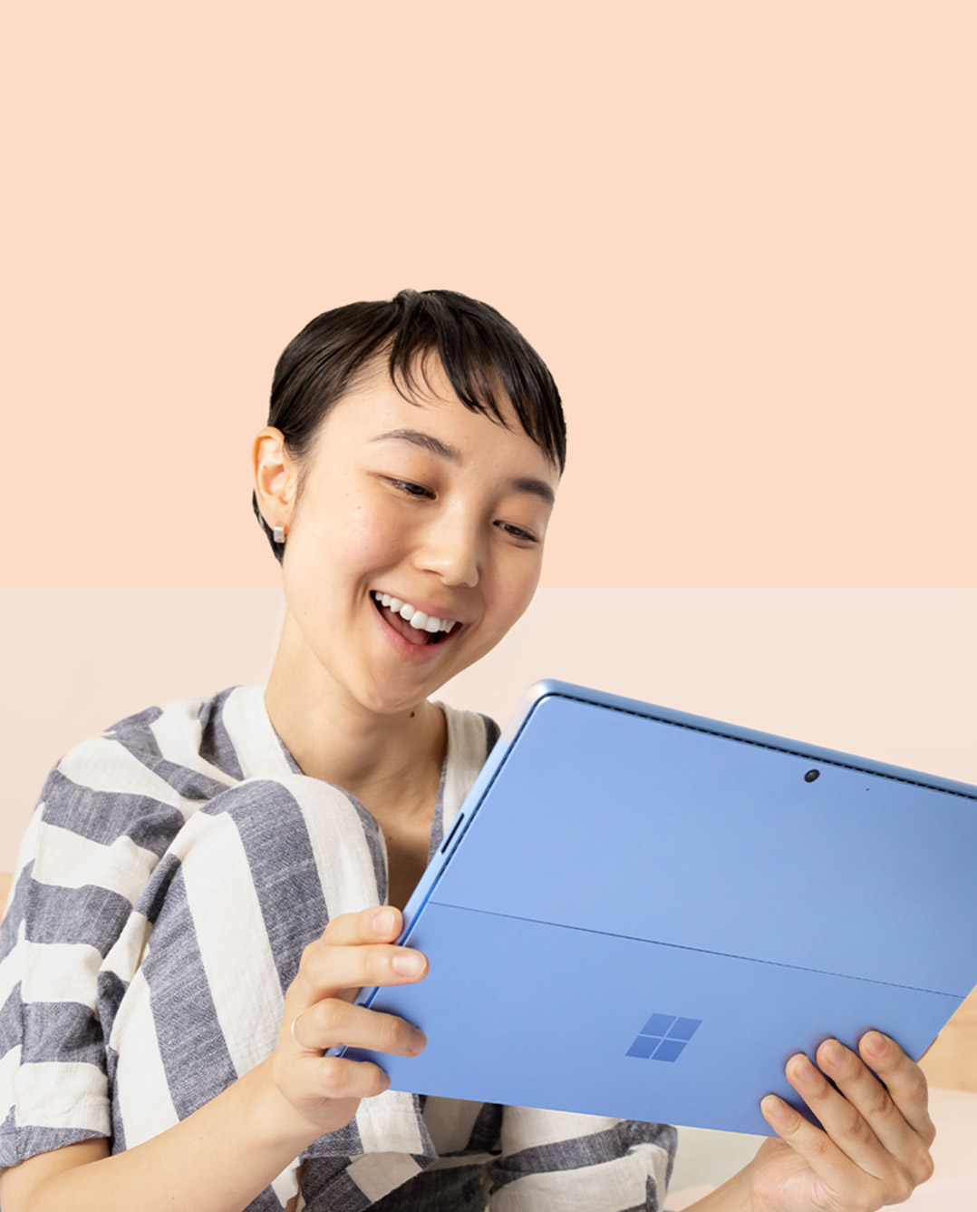 Een vrouw lacht naar haar Surface Pro 9 in Sapphire terwijl ze een Surface Slim Pen 2 vasthoudt.