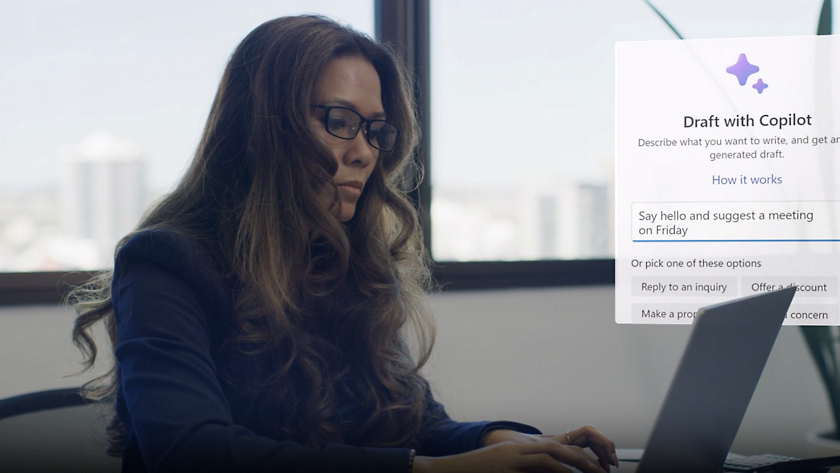 A woman is using a laptop in front of a screen.