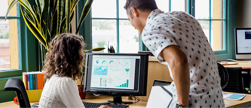 Two person in office looking at a dashboard in computer and having a discussion