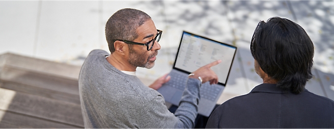 Two persons talking and pointing at a computer