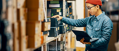 A person holding a tablet and looking at boxes