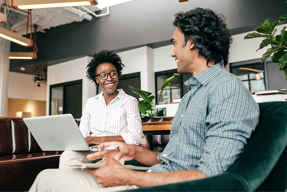 Two professionals, a black woman and a middle eastern man, having a discussion with a laptop on a table