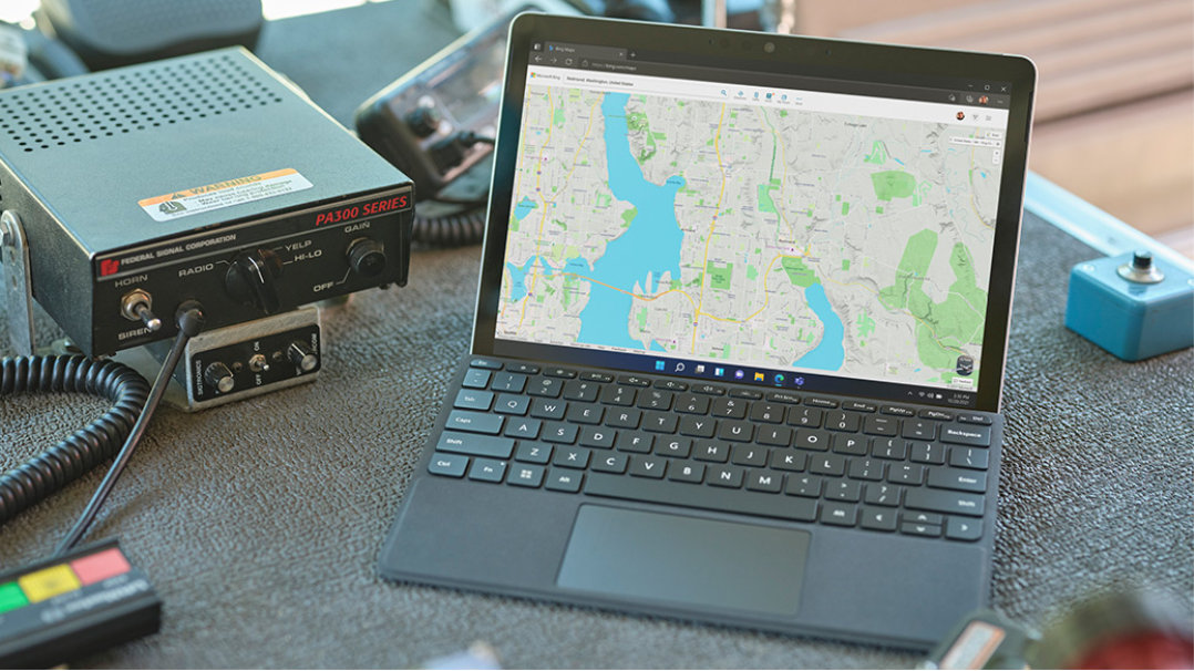 Se muestra un dispositivo Surface Go 3 junto a la radio de un agente de primeros auxilios. Se muestra un mapa en la pantalla.