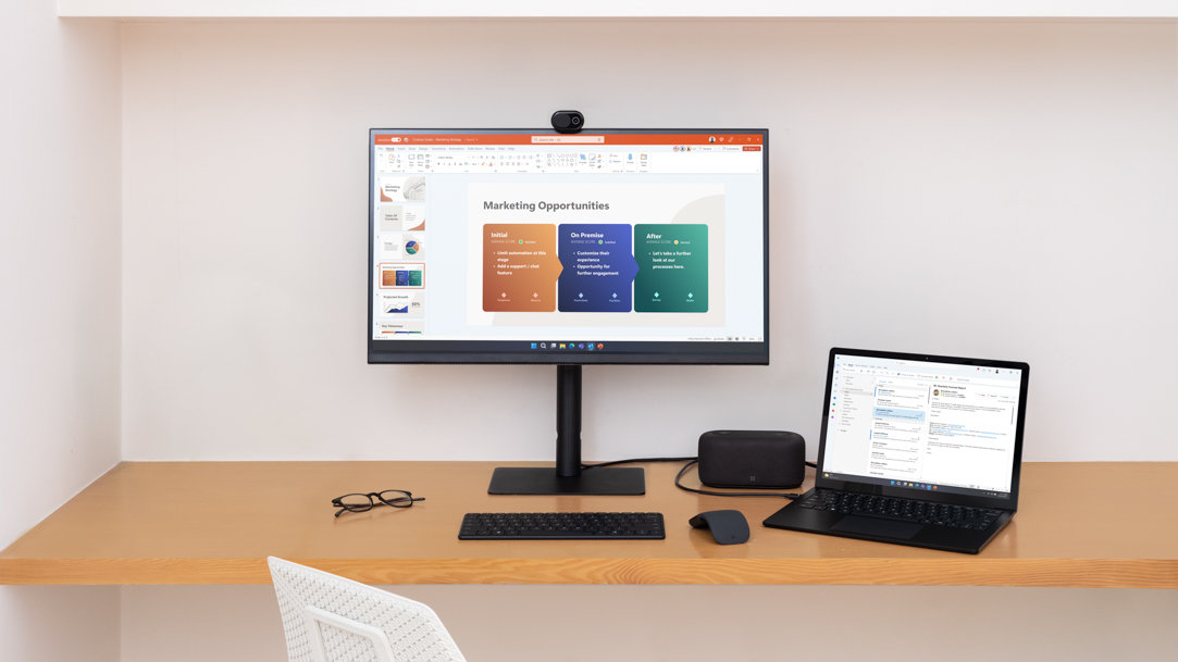 A Surface device and desktop screen on a wooden desk