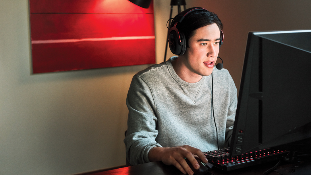 A man wearing a headset and mic while typing on a Windows laptop