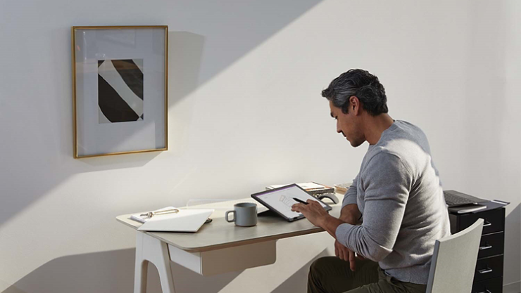自宅のオフィスで Surface ペンと Surface Pro を使用している男性