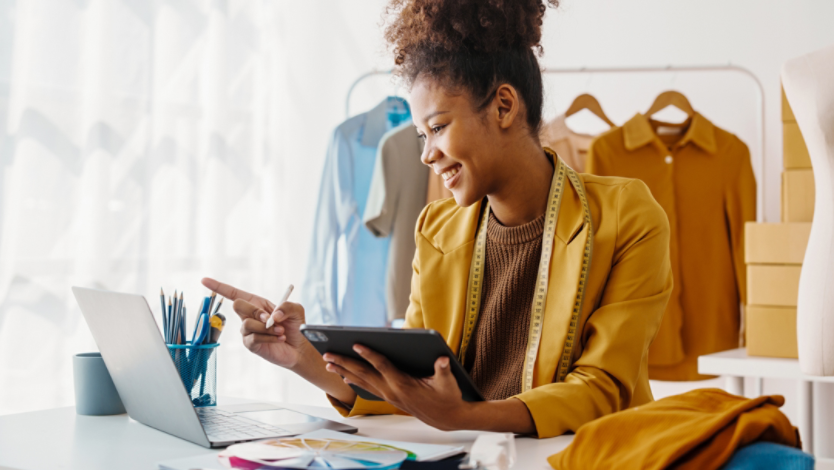 A fashion designer using a laptop and a tablet