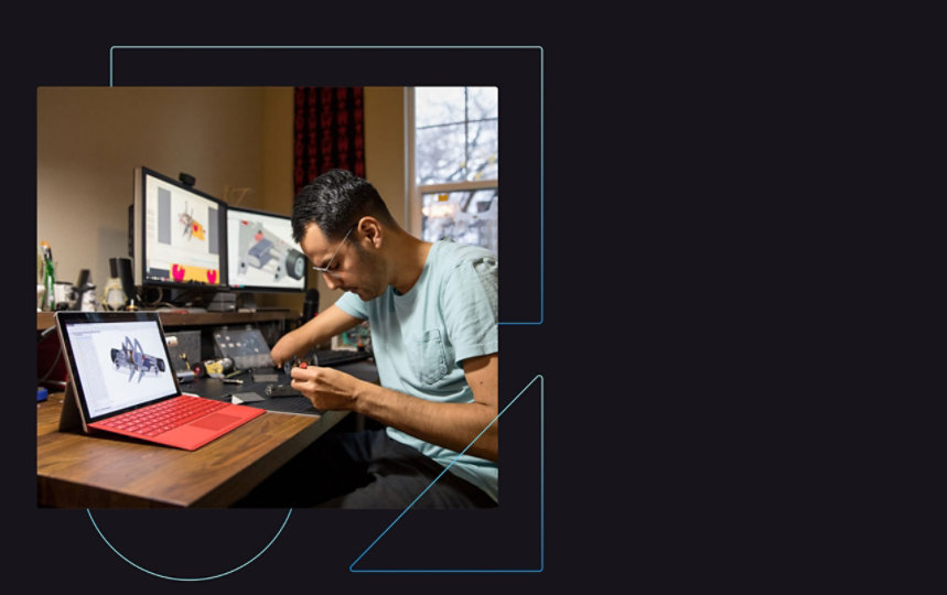 Man sitting at desk working with dual monitors and notetaking materials.