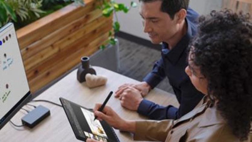 En person bruker håndskrift på Surface Go 3 mens en annen ser på