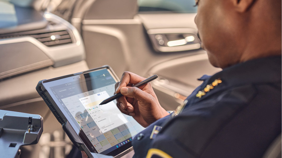 Se muestra un policía en su coche que usa el Lápiz para Surface para escribir en su dispositivo Surface Pro