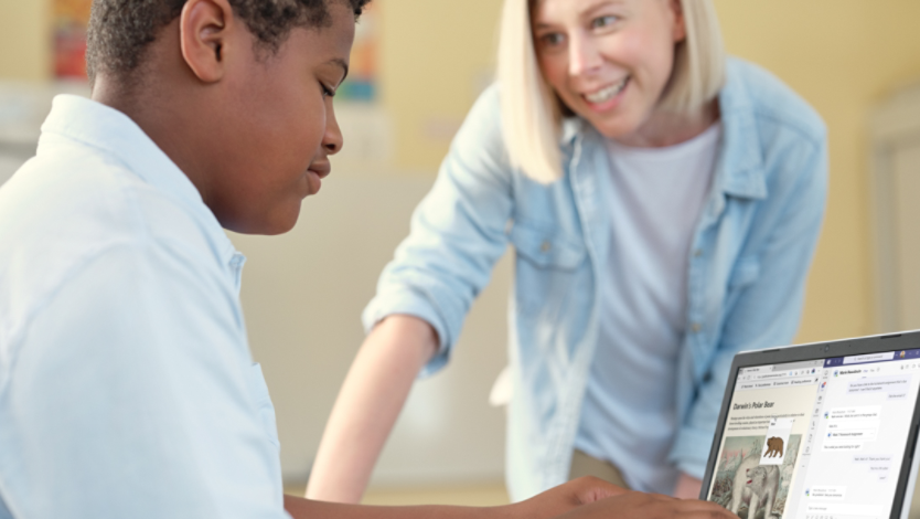 A teacher and student looking at a laptop