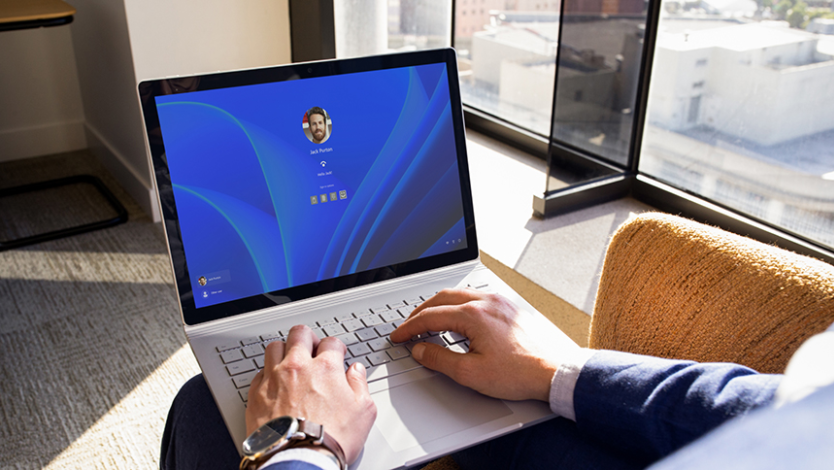 Ein Benutzer mit einem aufgeklappten Laptop, der von einem Windows Hello-Anmeldebildschirm begrüßt wird.