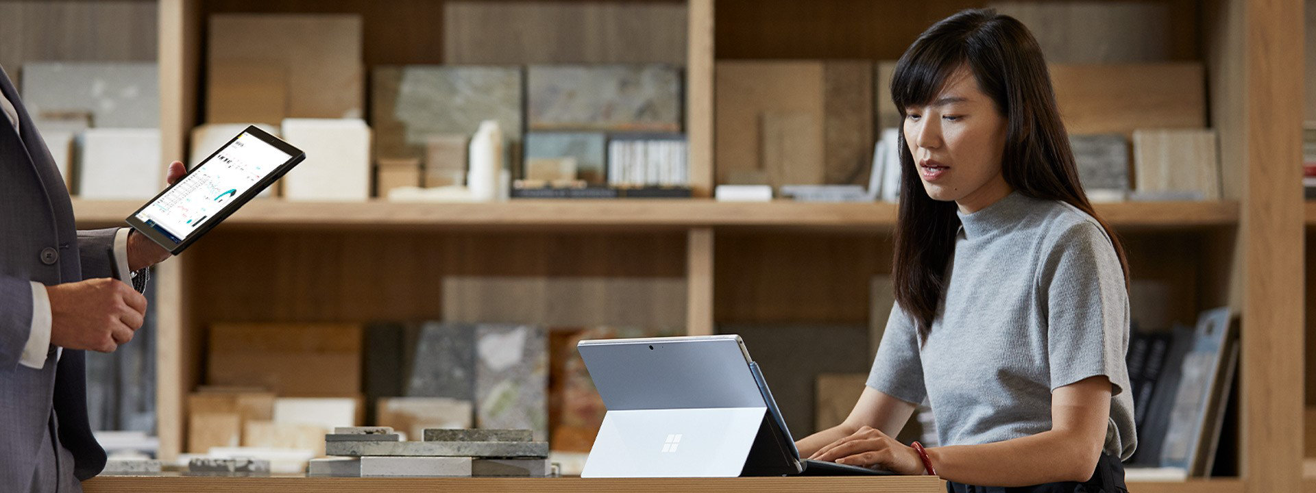 Una mujer y su colega hablan de negocios mientras trabajan en sus dispositivos Surface