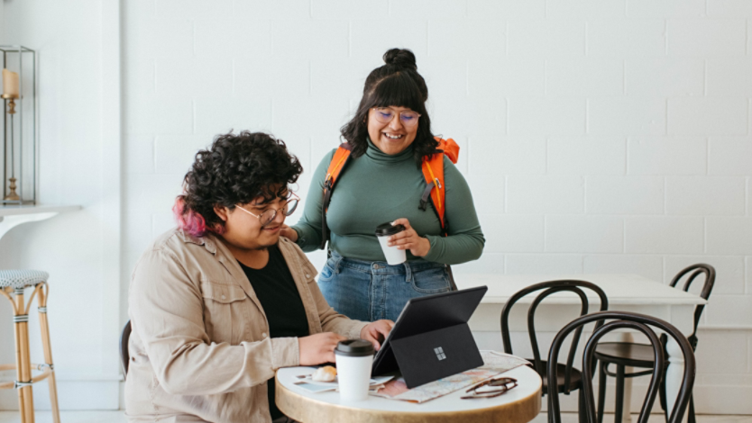 Couple sitting at a table in a café, looking at their computer