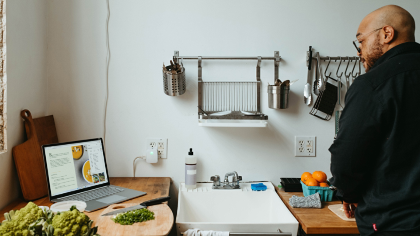 Man standing in his kitchen looking at his web browser