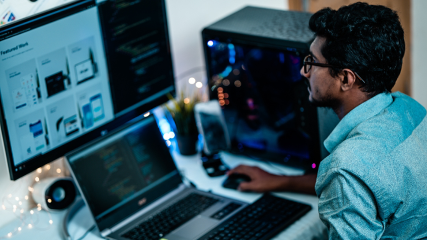 Man using Windows laptop and dual computer monitor