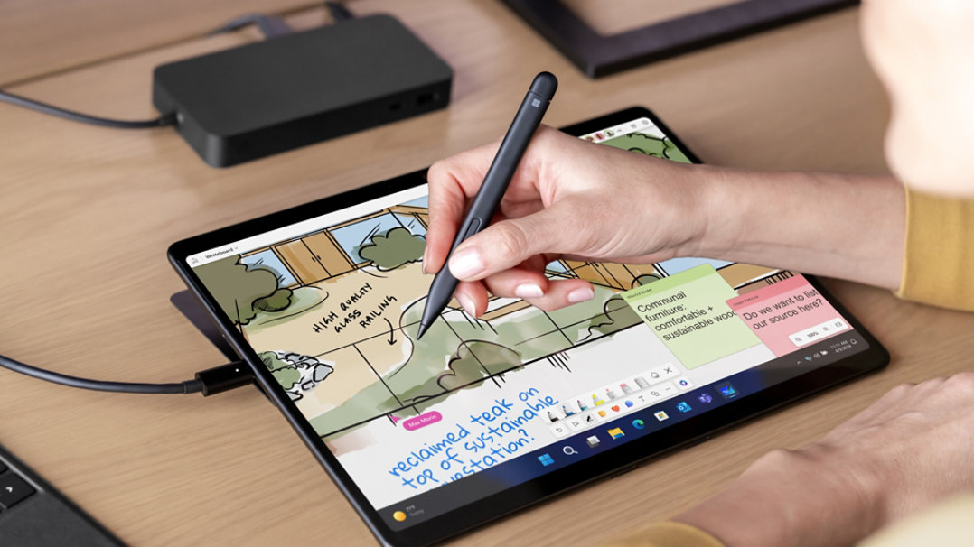 Osoba pozorovaná ostatními používá perem Surface Slim Pen na obrazovku zařízení Surface