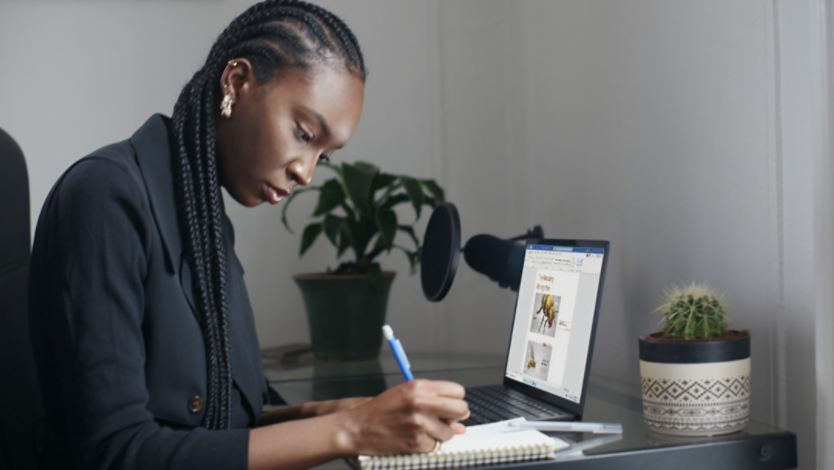 Student taking notes while using a Surface laptop