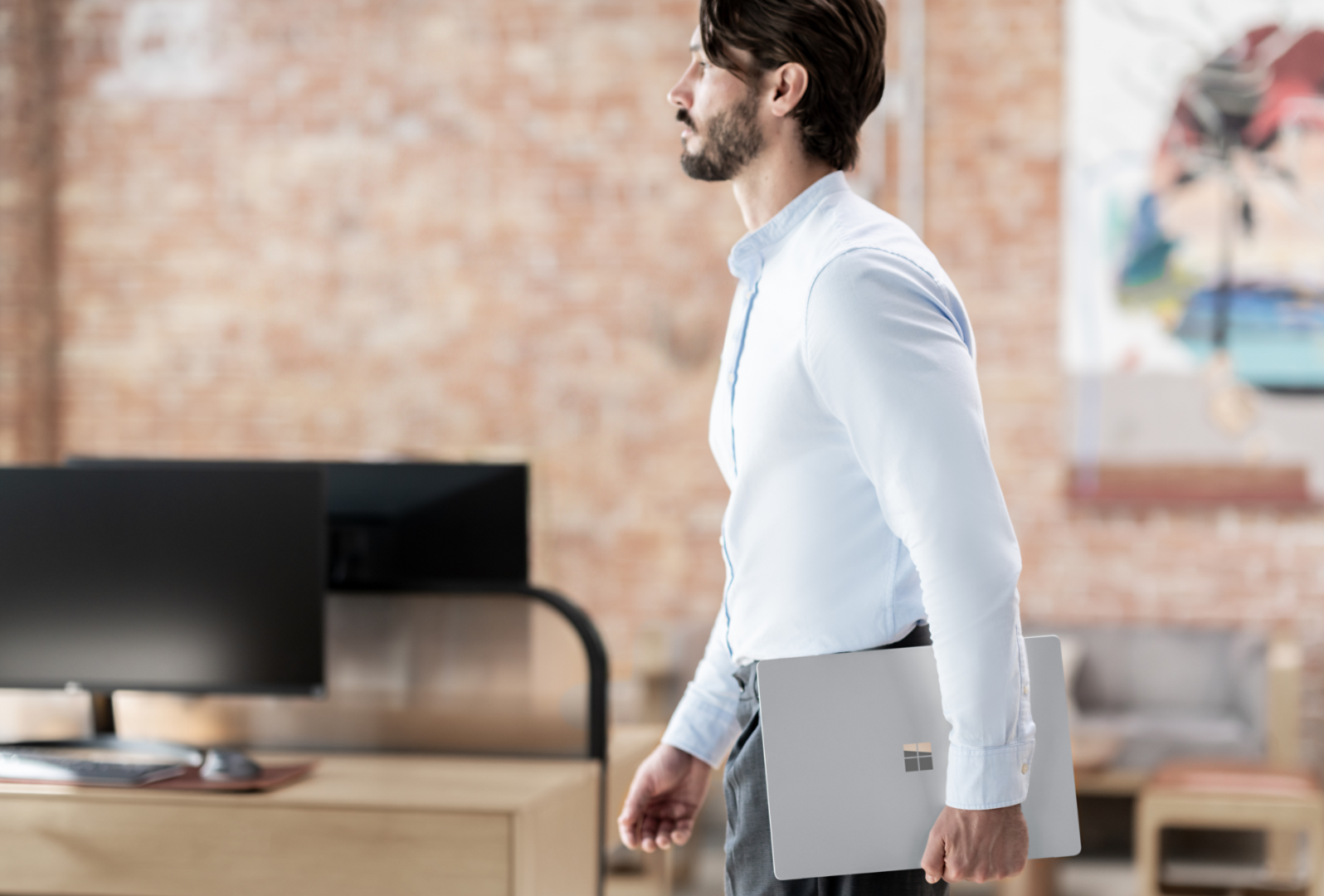 Man walking and holding Surface Laptop 6