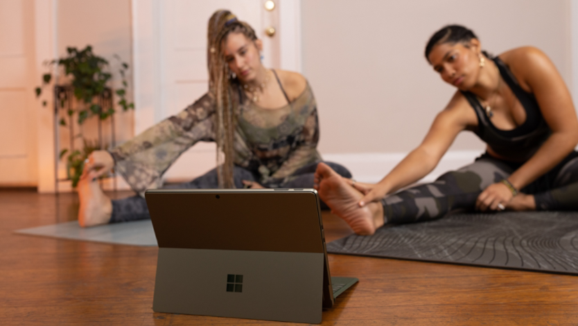 Two women doing yoga in front of a Surface