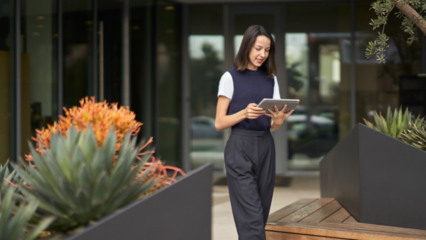 a woman looking at her Surface 2-in-1 PC while walking outside