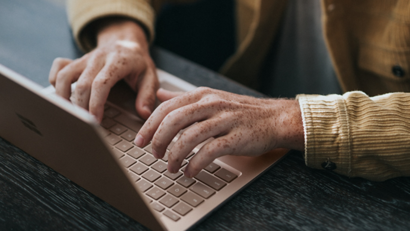 a man in yellow dress shirt using Microsoft Surface Laptop