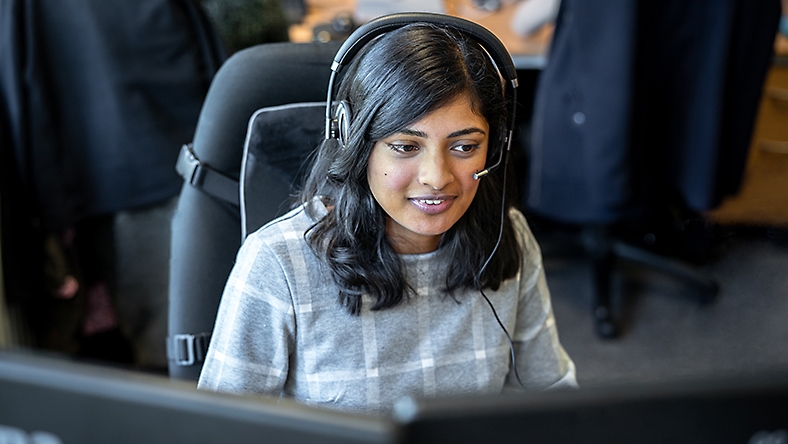 Een klantenservicemedewerker met een headset op lacht