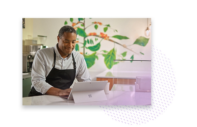 A café employee wearing an apron and using a tablet