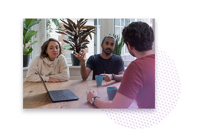 Drie personen hebben een vergadering met koffie en een laptop