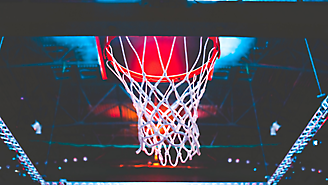 A basketball hoop with a net, viewed from below with a red glow in the background