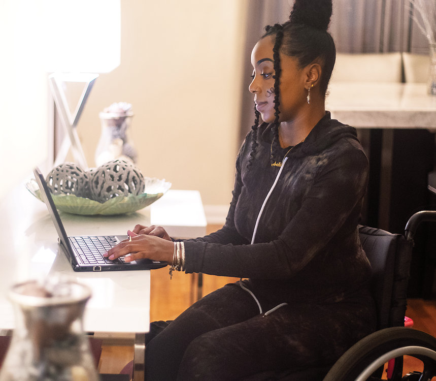 A person who uses a wheelchair works from home at a desk. 