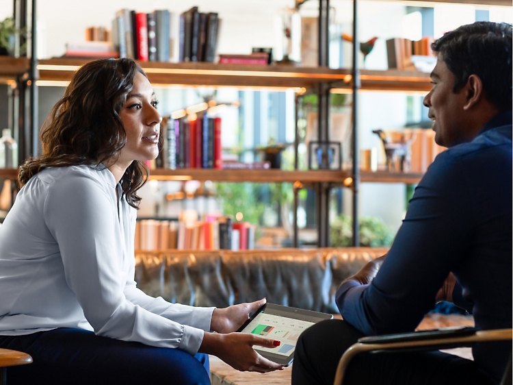 Two colleagues are seated in an office setting, engaged in a discussion. 