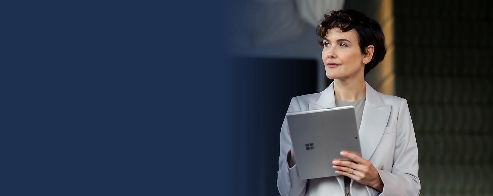 Professional woman holding a tablet and looking into the distance.