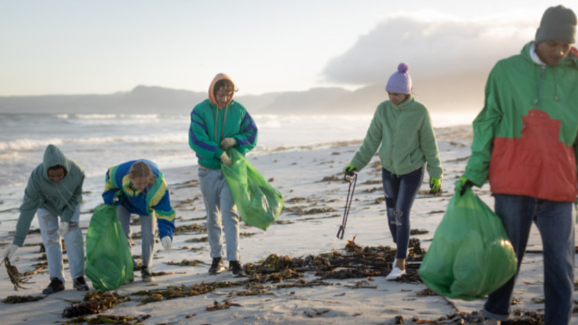 A group of five young volunteers cleaning a beach.