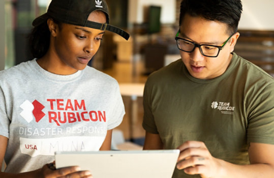 Dos miembros del equipo de Team Rubicon miran juntos una tableta.