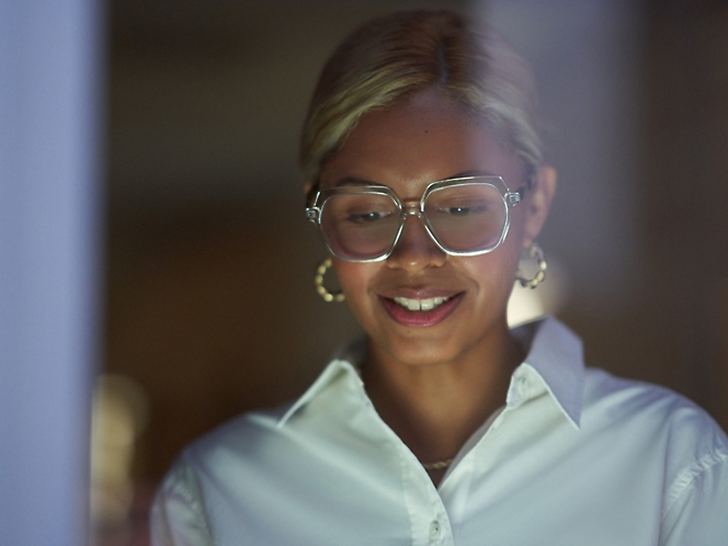 A woman wearing spectacles looking down in the screen