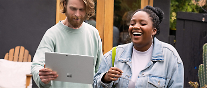 En mann og en kvinne som ler mens de holder et Microsoft Surface-nettbrett.