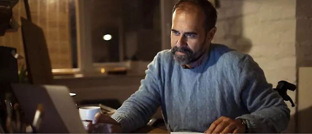 A person holding a cup working on laptop