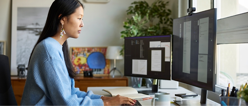 A woman working with multiple screens