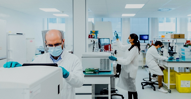 Three lab workers doing tasks in a lab