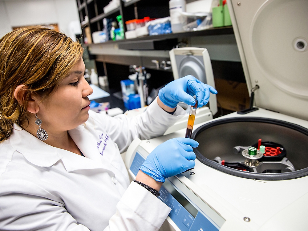 A person in a lab coat holding a tube with liquid