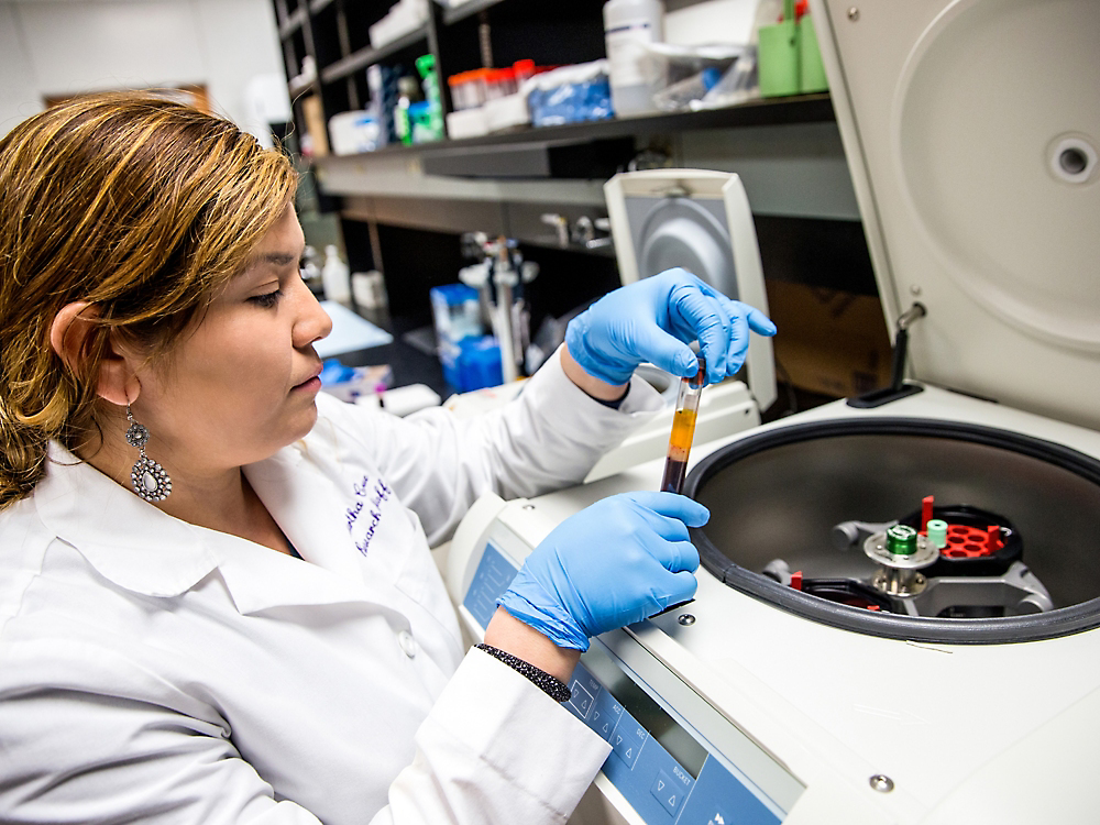 Personne dans une blouse de laboratoire tenant un tube avec du liquide