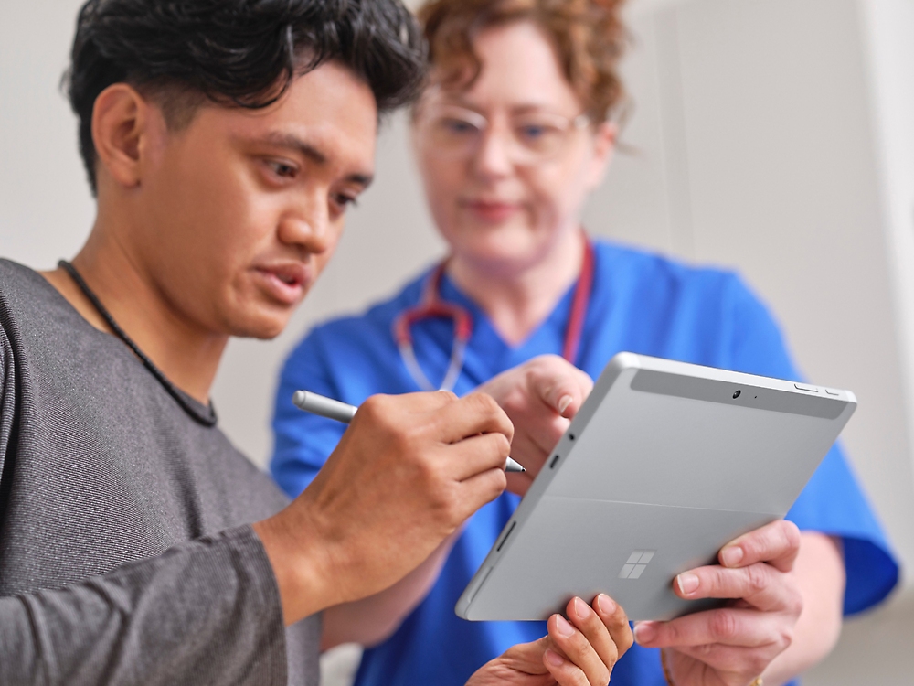 A person and another individual looking at a tablet