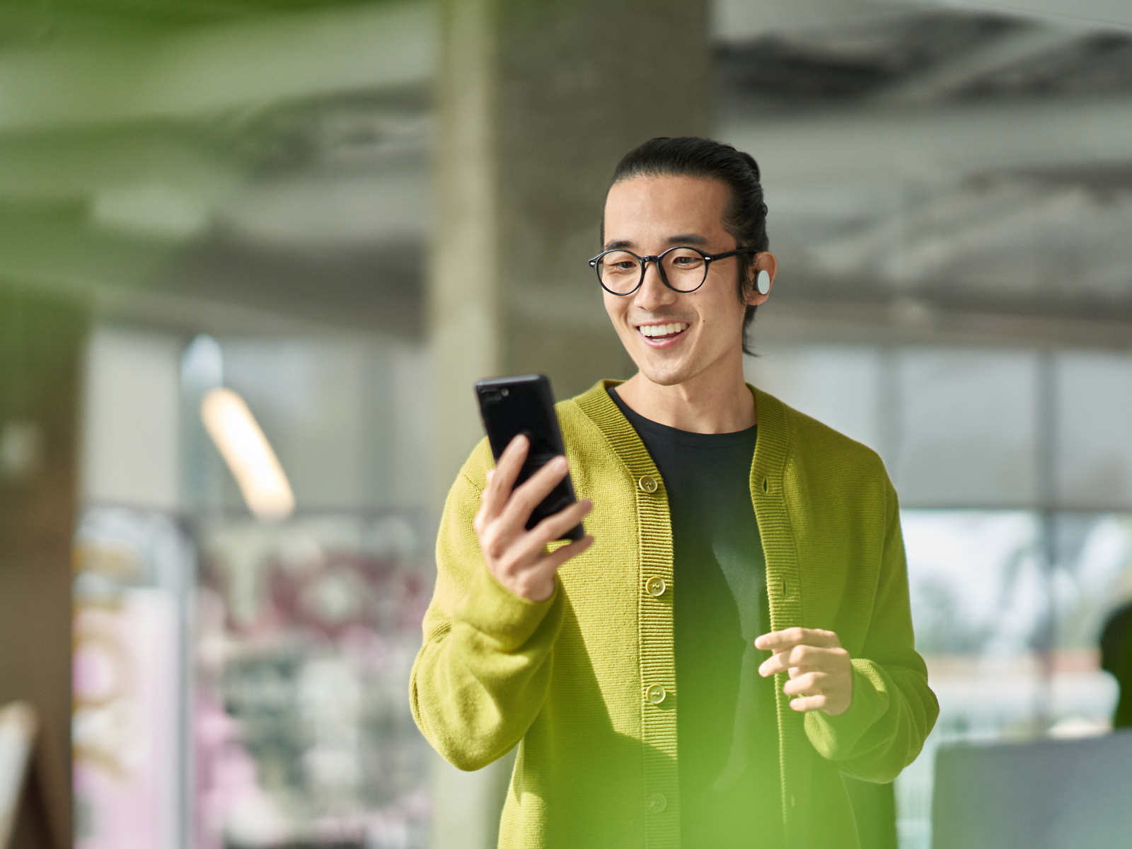 Een glimlachende persoon die naar een telefoon kijkt