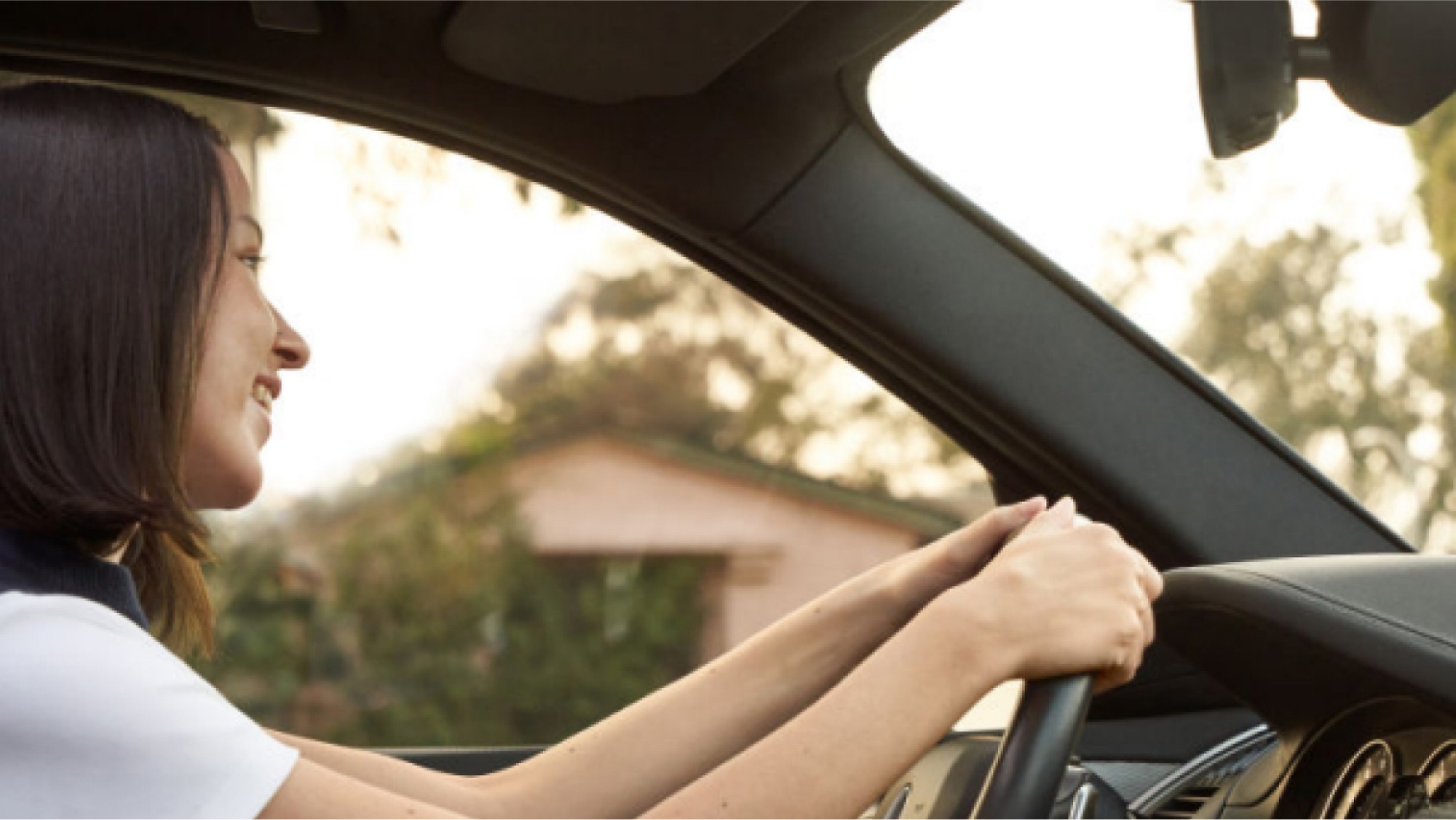 A woman driving a car with her hands on the steering wheel.