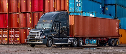 En semittruck er parkert foran containere.