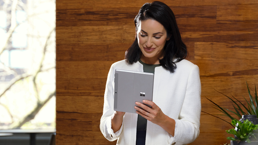 Nainen seisoo kirjoittaessaan Surface Go 4 -laitteella tablettitilassa