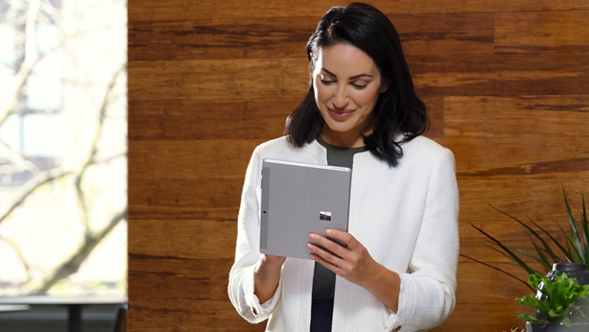 A woman stands while writing on Surface Go 4 in tablet mode