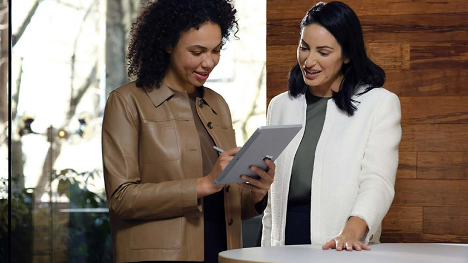 Kaksi työntekijää kokouksessa siirtyy Surface-kynällä paikasta toiseen Surface Go 4 -laitteessa