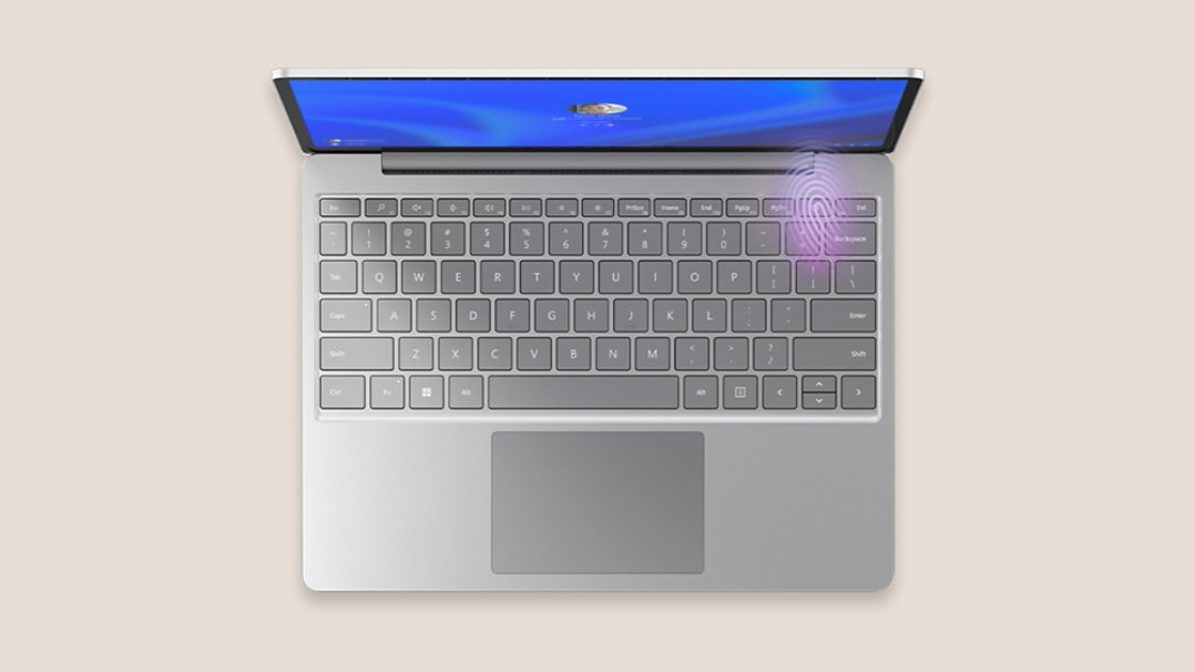 Pohled shora na Surface Laptop Go 3 v platinové barvě s podsvícenou čtečkou otisků prstů v pravém horním rohu klávesnice.